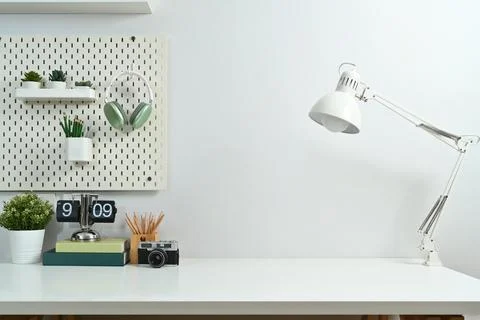 Creative workplace with lamp, camera, lamp, books, houseplant and peg board on Stock Photos