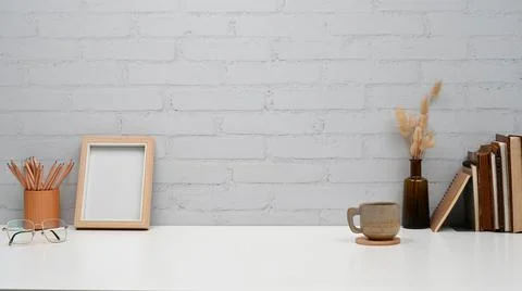 Creative workspace with picture frame, pencil holder, books and coffee cup on Foto stock