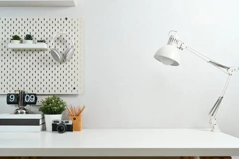 Creative workspace with retro camera, books, lamp and houseplant against white Stock Photos