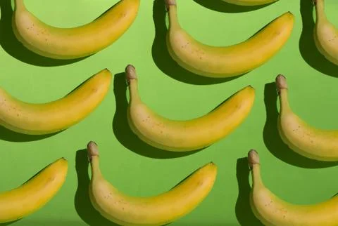 Creative yellow bananas pattern on green background. Stock Photos