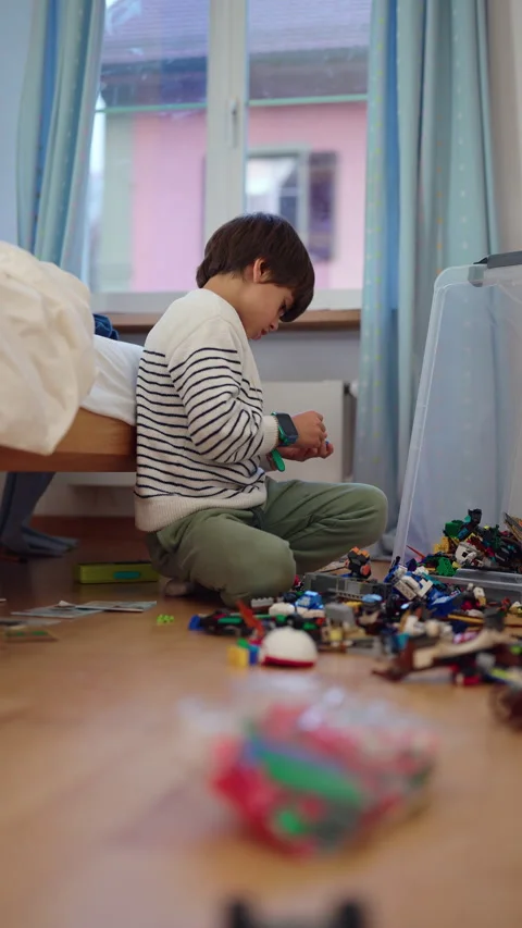 Creative young boy builds a toy vehicle with construction blocks on the bed.. Stock Footage 343652654