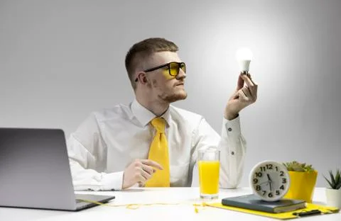 Creative young man looking at burning light bulb in hand. Startup business idea Stock Photos