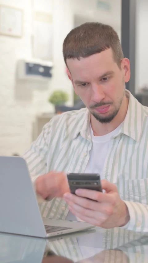 Creative Young Man Working on Laptop and Using Smartphone, vertical video Vidéo 325563918