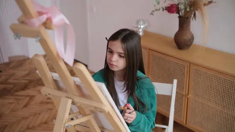 Creative young student with a pencil behind her ear sitting in front of a wooden 库存影片 345042355