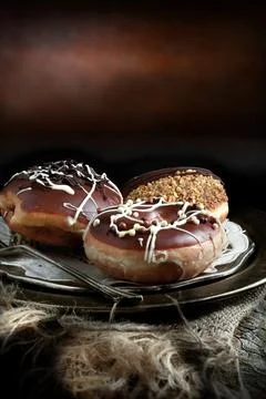 Creatively lit donuts smothered in thick chocolate, icing and toppings agai.. Stock Photos