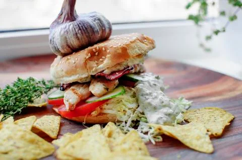 Creatively styled beef burger rustic home made chips or crisps Garlic on top Stock Photos