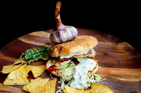 Creatively styled beef burger rustic home made chips or crisps Garlic on top Stock Photos