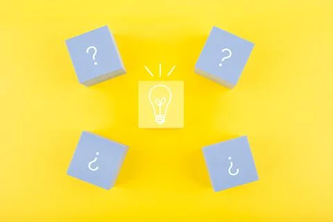 Creativity and fresh ideas concept. Light bulb and question signs drawn on toy Stock Photos