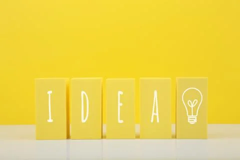Creativity concept. Idea written on yellow toy blocks and drawn light bulb Stock Photos