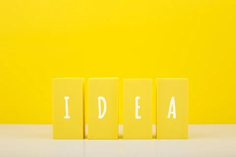 Creativity concept. Idea written on yellow toy blocks against bright yellow Stock Photos