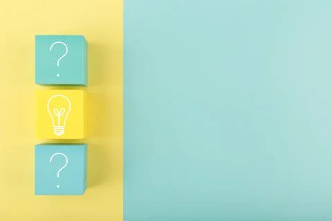 Creativity concept. Light bulb and question signs drawn on toy cubes on yellow Stock Photos