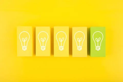 Creativity concept. Light bulbs on yellow and green toy blocks against bright Stock Photos