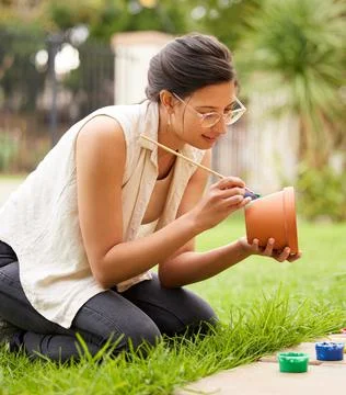 Creativity doesnt wait for that perfect moment. s young woman painting a pot in Stock Photos