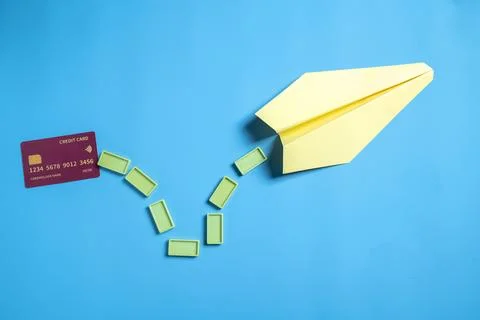 Credit card and rectangular blocks with a yellow paper airplane on a blue b.. Stock Photos
