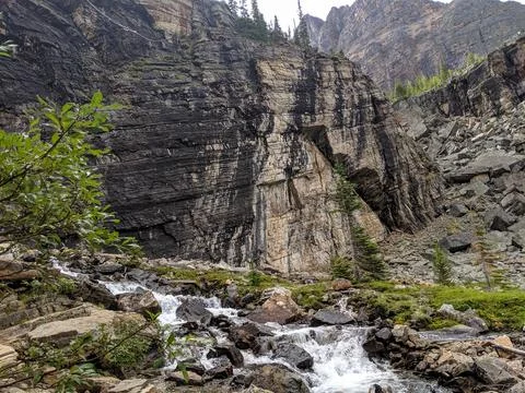 A creek flows down through textured rock in the mountains Foto stock