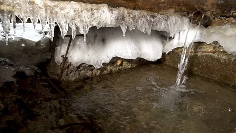 A creek rumbles. A source of artesian water flows into a winter frost in a stron Stock Footage 99632877