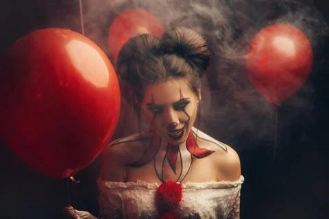 Creepy beautiful woman in image of a scary clown. Carnival outfit white dress Stock Photos