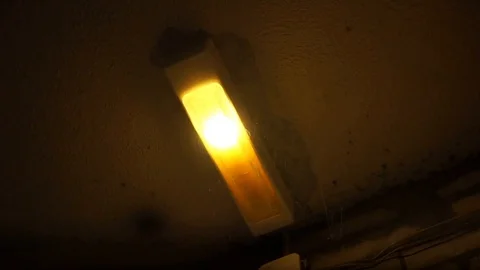A creepy lamp in a web flickers on the ceiling in a scary corridor near a brick Stock Footage 113819630