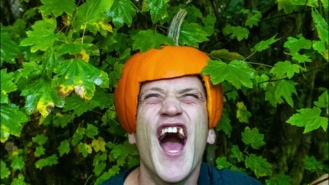 Creepy man laughing with missing teeth while wearing a pumpkin helmet for Hallow Stock Footage 96273086