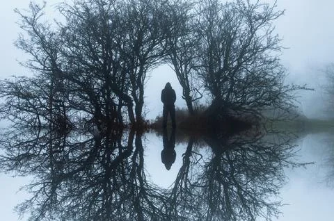 A creepy reflection upside down edit, of a hooded figure Stock Photos