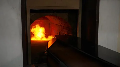 In the crematorium, a coffin with a dead body drives into a chamber with a fire. Stock Footage 309156953