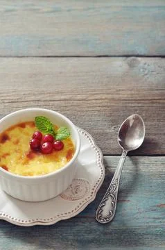 The creme brulee in ceramic baking mold with mint and berries on wooden table Stock Photos