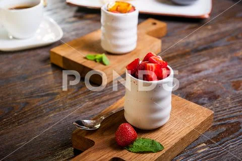 Creme brulee (cream brulee, burnt cream) with strawberries served on wooden b Stock Photos