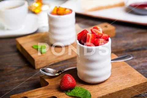 Creme brulee (cream brulee, burnt cream) with strawberries served on wooden b Stock Photos