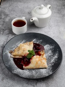 Crepes with cherry jam folded in triangles decorated with powdered sugar, on  Stock-Fotos