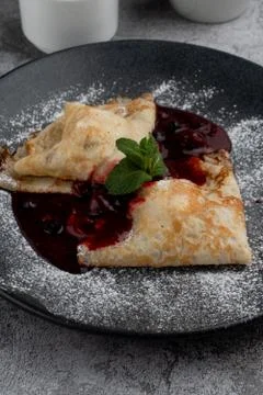 Crepes with cherry jam folded in triangles decorated with powdered sugar, on  Stock Photos