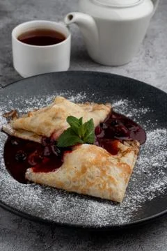 Crepes with cherry jam folded in triangles decorated with powdered sugar, on  Stock Photos