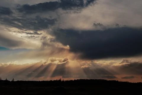 Crepuscular Rays Breaking Through Dramatic Clouds at Sunset Stock Photos