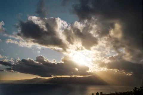 Crepuscular rays through clouds over a mountain in golden hour Stock Photos