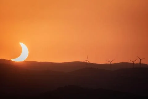 Crescent Eclipse Setting over Wind Turbines Stock Photos