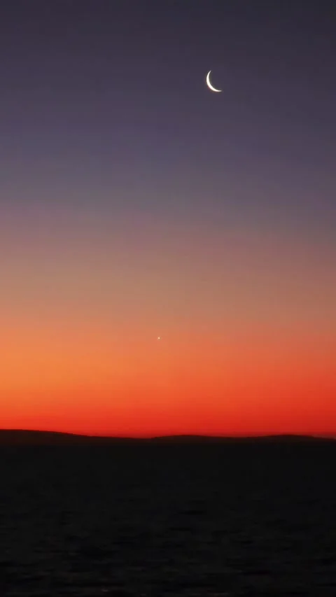 Crescent moon and star over a silhouetted horizon at sunset. Stock Footage 312517031
