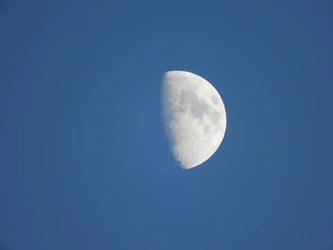 Crescent moon hangs in deep blue sky Stock Photos