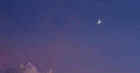 Crescent moon hiding behind pink cloud at twilight. Stock Footage 248659437