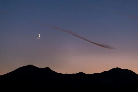 Crescent moon over mountain range Stock Photos