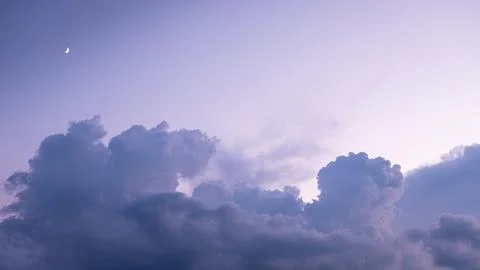 Crescent moon rises over dramatic cloudscape at dusk Stock Photos