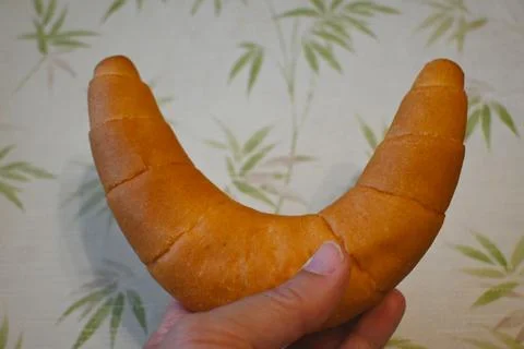 Crescent-shaped bread roll held in hand Stock Photos