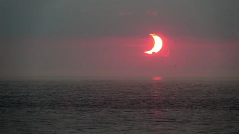 A crescent-shaped partial solar eclipse at sunrise over the Atlantic Ocean Stock Footage 155670010