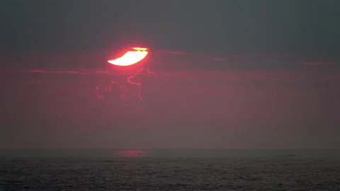 A crescent-shaped partial solar eclipse at sunrise disappears behind a Stock Footage 155670112