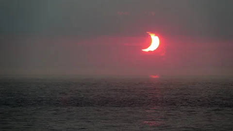 A crescent-shaped sun rises over the Atlantic Ocean during a partial solar Stock Footage 155669840