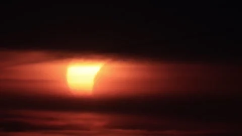 Crescent sun emerging through dark clouds during partial solar eclipse at s.. Stock Footage 342277836