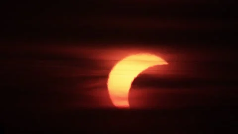 Crescent sun emerging through dark clouds during partial solar eclipse at s.. Stock Footage 342285578
