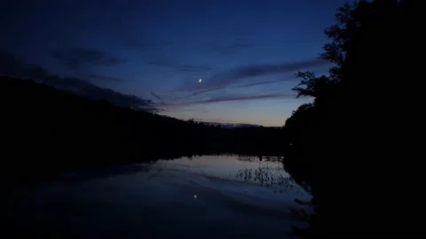Crescent moon reflected on lake at dusk Stock Footage 157856582
