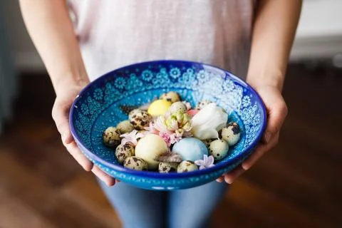 Cretan bowl with Easter eggs and flowers in the hands of a girl Stock Photos