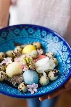 Cretan bowl with Easter eggs and flowers in the hands of a girl Stock Photos