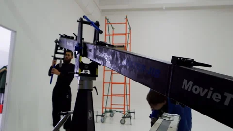 Crew assembles massive camera jib in bright empty room Vídeos de archivo 308949356