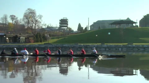 A crew boat team rows with shore in background Stock Footage 997348